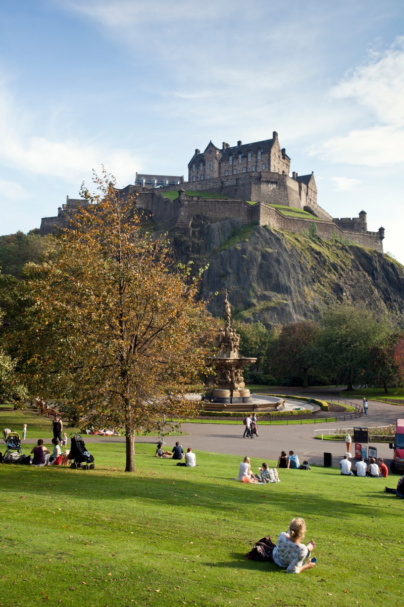 A day out in Edinburgh. A family with two children in Princes Street gardens. View up to Edinburgh castle on Castle Rock. Britain 100.